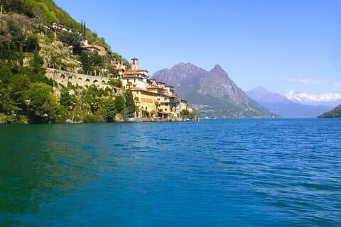 View from Lake Lugano toward Gandria and beyond to snow-covered mountains in Italy